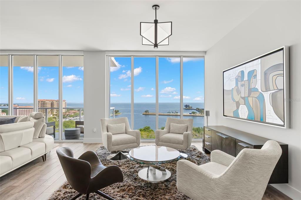A modern living room features floor-to-ceiling windows with a panoramic view of the ocean — 176 4TH AVENUE NE UNIT 1102, ST PETERSBURG, FL
