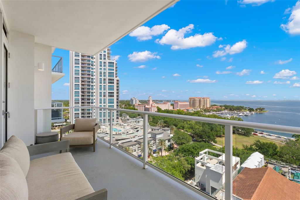 A balcony with outdoor seating overlooks a city skyline, a park, and a large body of water — 176 4TH AVENUE NE UNIT 1102, ST PETERSBURG, FL