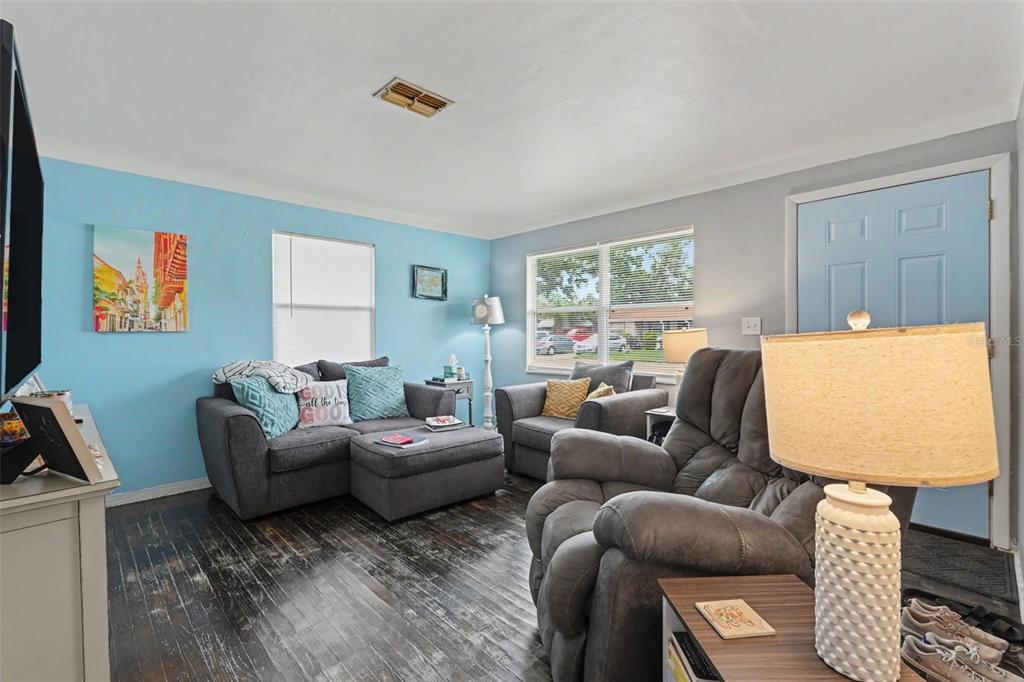 A living room features dark wood floors, light blue walls, and gray upholstered furniture — 2311 35TH STREET S, ST PETERSBURG, FL
