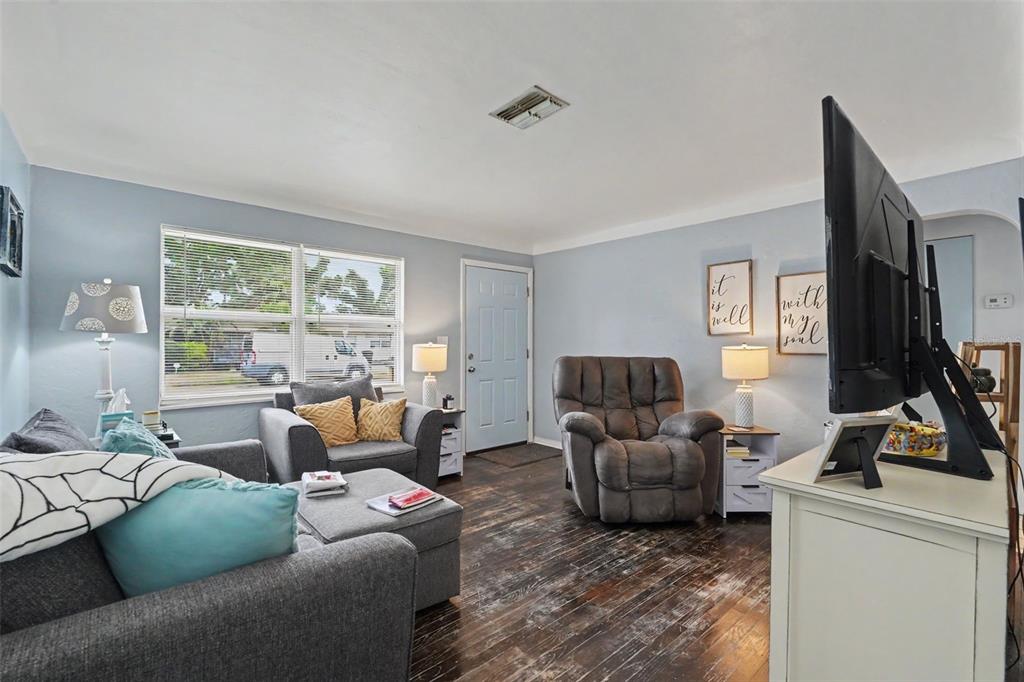 A living room features gray furniture, light blue walls, and dark wood-look flooring — 2311 35TH STREET S, ST PETERSBURG, FL