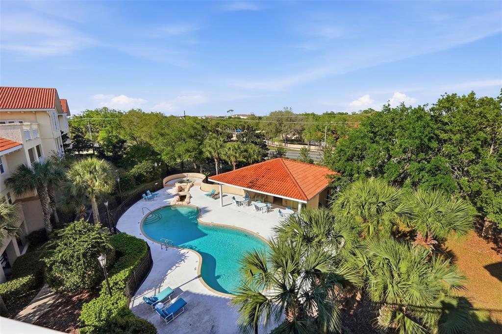 An elevated view of a swimming pool with a covered patio and surrounding palm trees — 200 BELLA HARBOR COURT UNIT 113, PALM COAST, FL