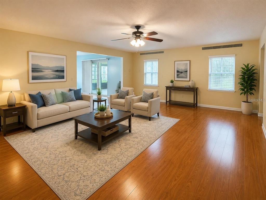 A living room features light yellow walls, hardwood floors, a ceiling fan, and neutral furniture — 999 GILLESPIE DRIVE, PALM HARBOR, FL