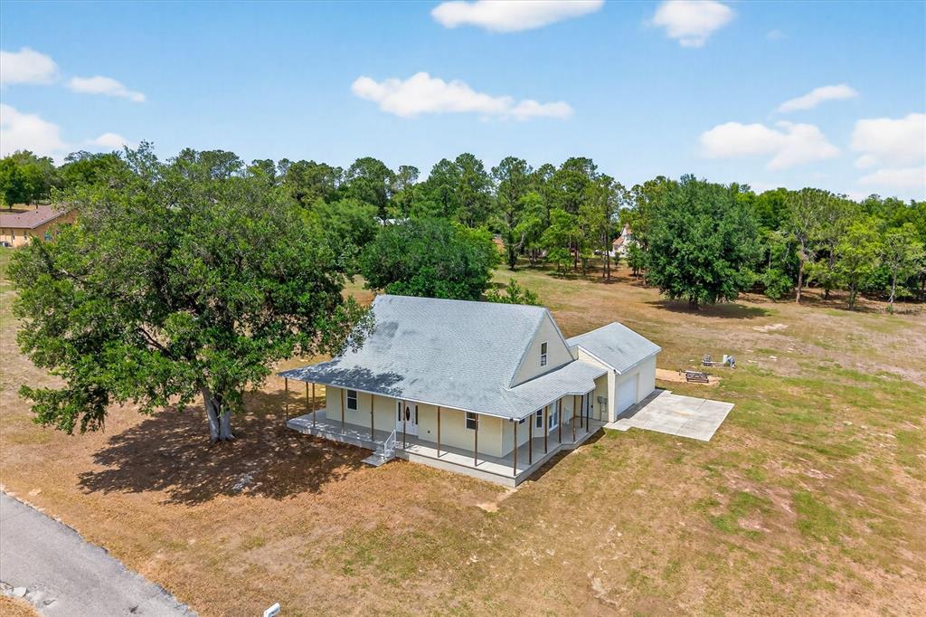 An aerial view shows a light-colored house with a wrap-around porch and attached garage — 38327 HAMRICH DRIVE, DADE CITY, FL