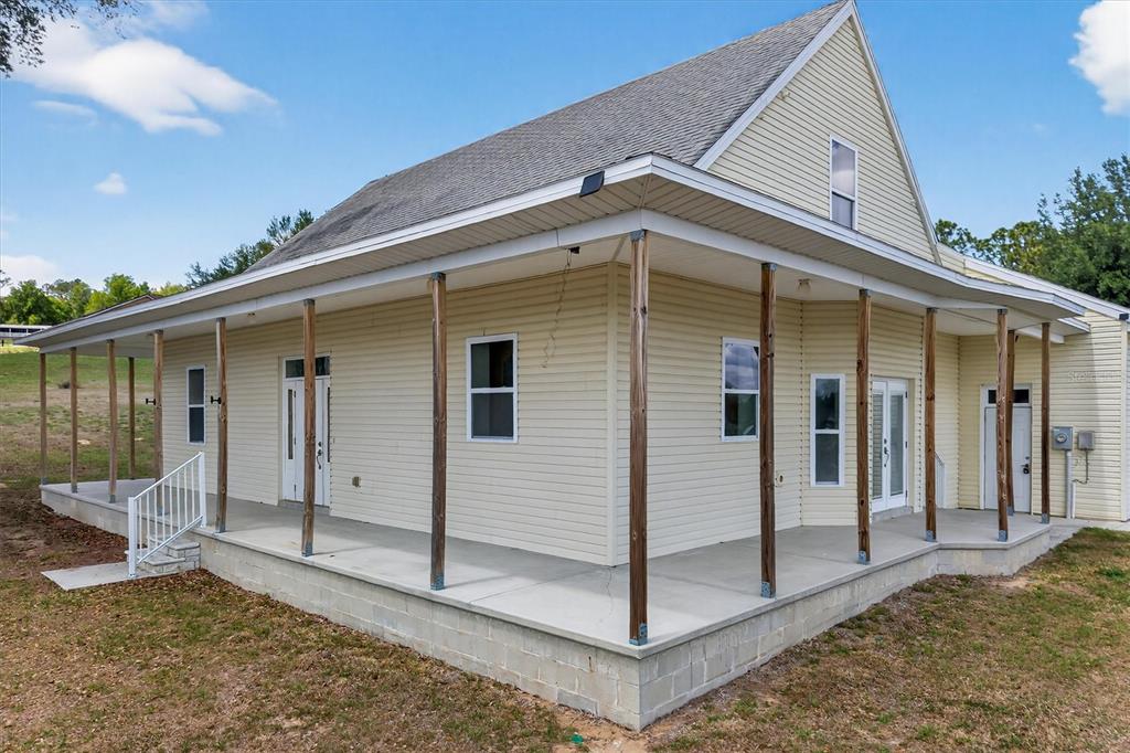 A light-colored house with a wrap-around porch and exposed wooden support posts — 38327 HAMRICH DRIVE, DADE CITY, FL