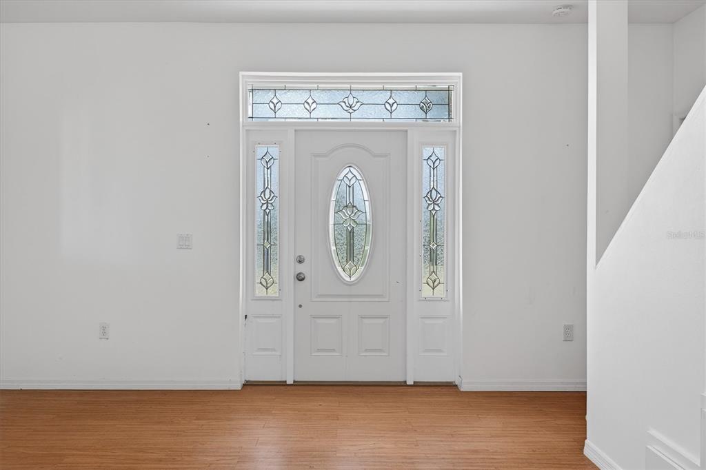 An entryway features a white front door with decorative glass panels and wood-look flooring — 38327 HAMRICH DRIVE, DADE CITY, FL