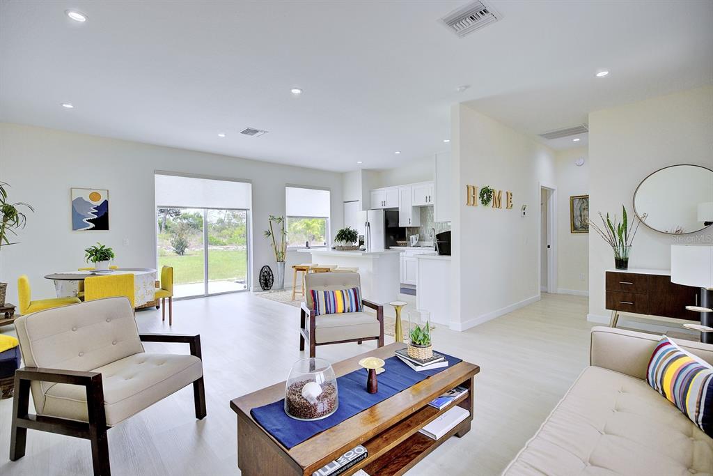 An open-concept living room and kitchen featuring light wood flooring and neutral-toned furniture — 109 FIRE ISLAND AVENUE NE, LAKE PLACID, FL