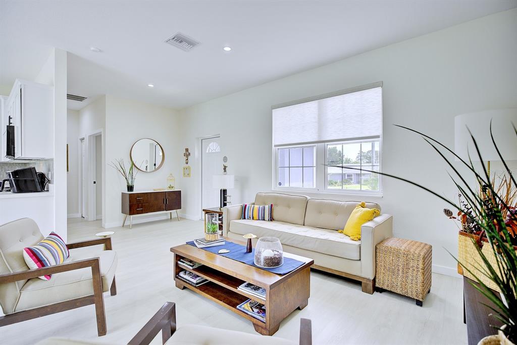 A bright living room features a beige sofa, wooden coffee table, and light-colored flooring — 109 FIRE ISLAND AVENUE NE, LAKE PLACID, FL