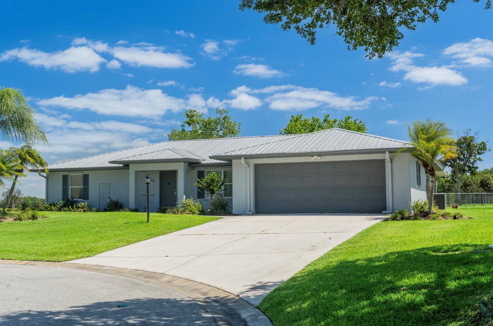 A single-story house with a gray metal roof, stucco exterior, and an attached two-car garage — 5264 SE 42nd Street, Okeechobee FL 34974, OKEECHOBEE, FL