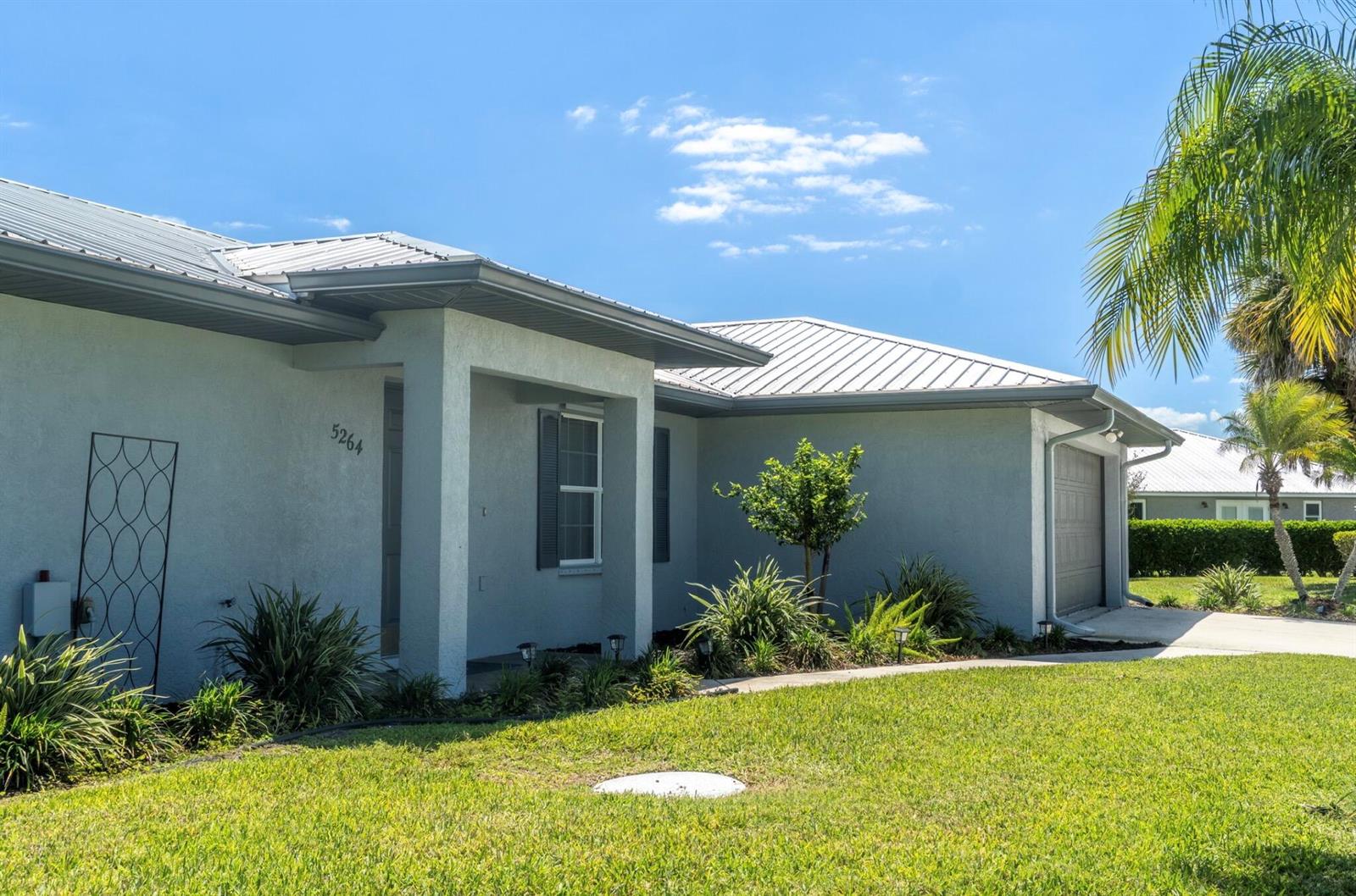 A single-story house with a light-colored stucco exterior, metal roof, and a front lawn — 5264 SE 42nd Street, Okeechobee FL 34974, OKEECHOBEE, FL