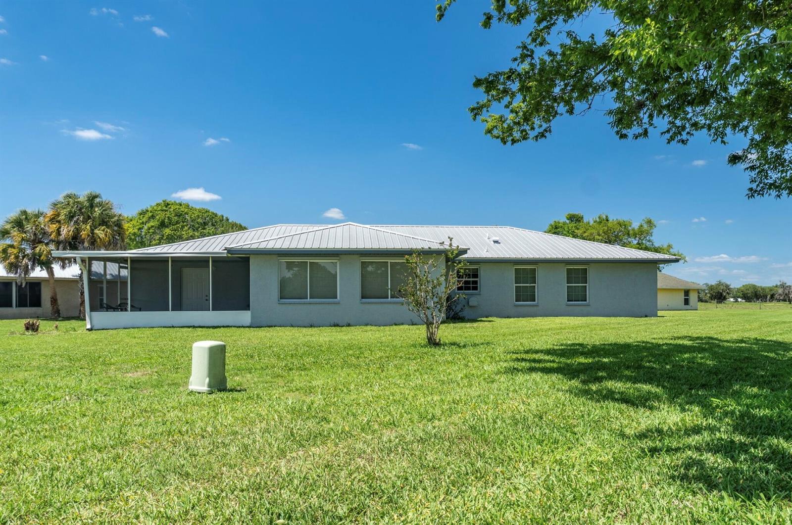 The exterior of a single-story house with a metal roof and a screened-in porch — 5264 SE 42nd Street, Okeechobee FL 34974, OKEECHOBEE, FL