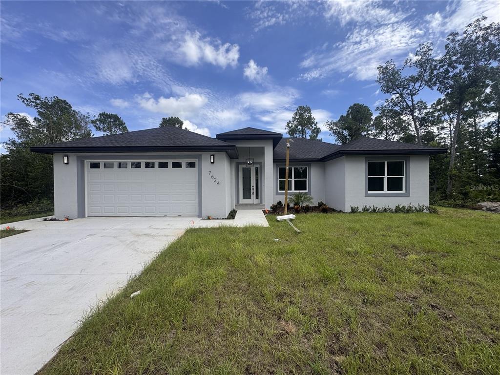 A single-story house with a gray stucco exterior, a two-car garage, and a concrete driveway — 7624 ANCHA STREET, SEBRING, FL
