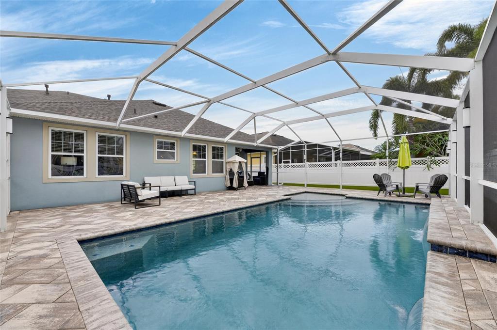 A backyard swimming pool with a screened enclosure, patio furniture, and a white fence — 513 MANNS HARBOR DRIVE, APOLLO BEACH, FL