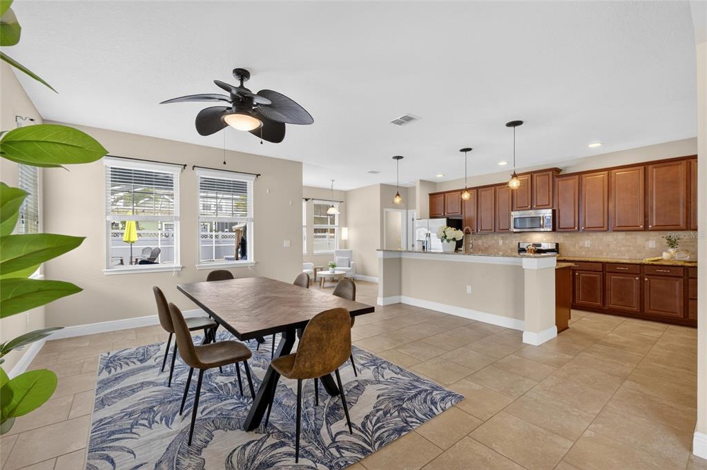 An open-concept kitchen and dining area features wood cabinets, tile flooring, and a ceiling fan — 513 MANNS HARBOR DRIVE, APOLLO BEACH, FL