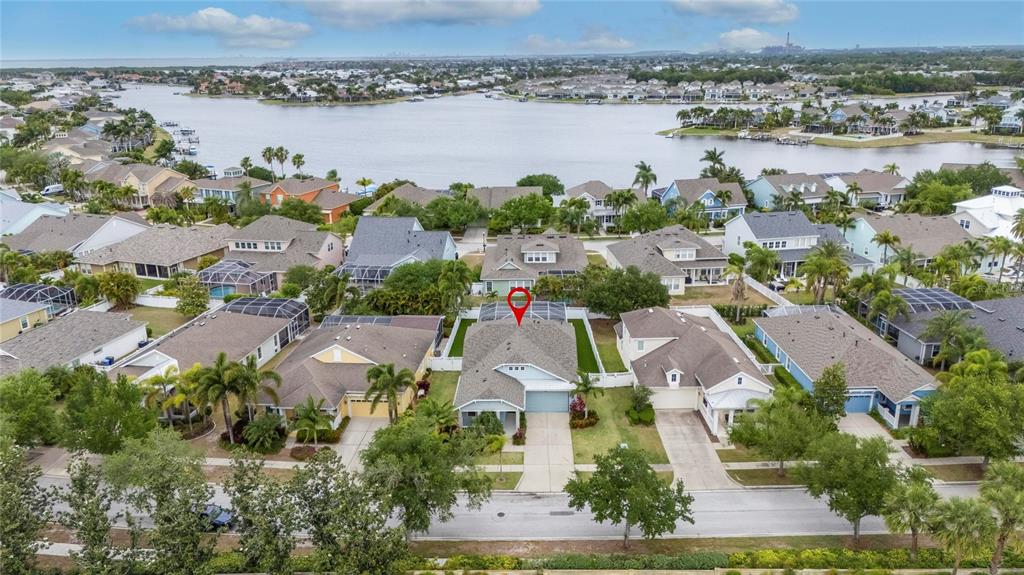 An aerial view shows a suburban house with a screened pool deck near a lake — 513 MANNS HARBOR DRIVE, APOLLO BEACH, FL