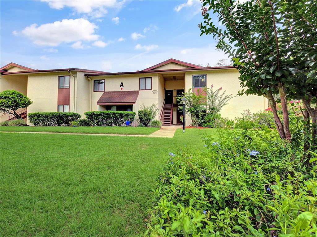 A two-story apartment building with a beige exterior, a central staircase, and a grassy lawn — 700 MIDWAY DRIVE UNIT B, OCALA, FL
