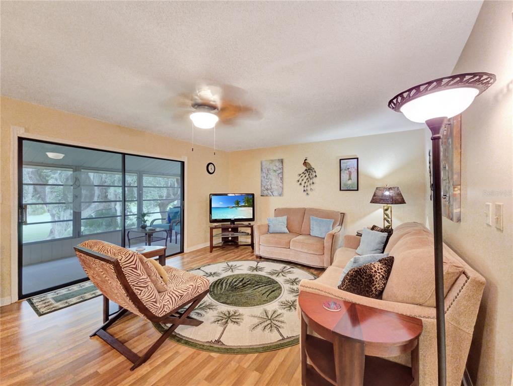 A living room features wood-look flooring, a circular area rug, a ceiling fan, and sliding doors — 700 MIDWAY DRIVE UNIT B, OCALA, FL