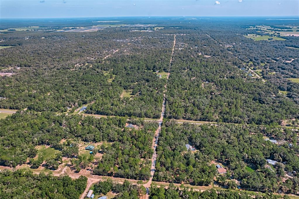 An aerial view shows a rural residential area with scattered houses nestled among dense trees — 000 NE 82ND PLACE, BRONSON, FL