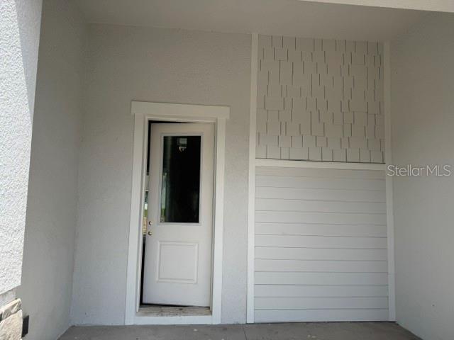 A white door with a glass pane sits next to a wall with horizontal and shingle siding — 140 FRONTIER DRIVE, PALM COAST, FL