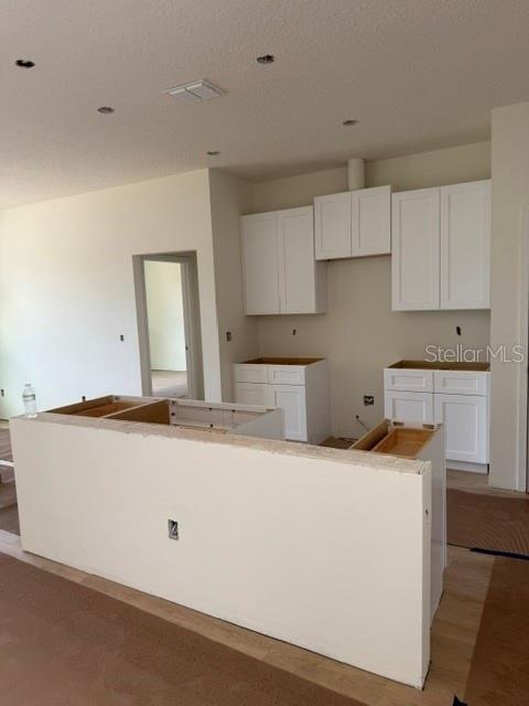 An unfinished kitchen features white cabinets, a central island, and light-colored flooring — 140 FRONTIER DRIVE, PALM COAST, FL