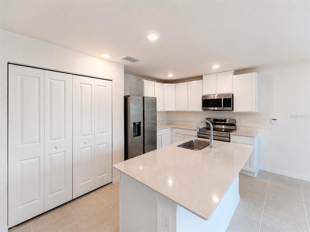 A kitchen features white cabinetry, stainless steel appliances, a center island, and light-colored countertops — 1691 2ND AVENUE, DELAND, FL