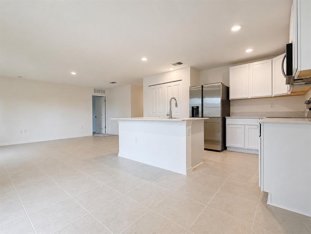 A kitchen with white cabinets, a central island, and stainless steel appliances on tiled floors — 1691 2ND AVENUE, DELAND, FL