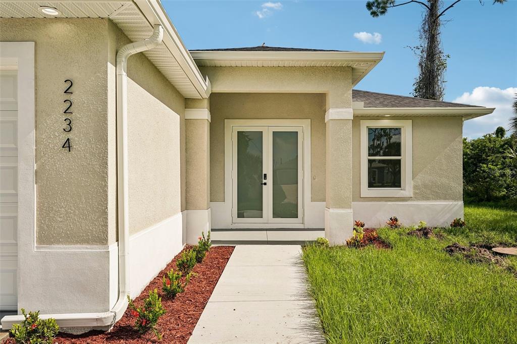 The exterior of a beige house features a concrete walkway leading to double front doors — 2234 JAMESON AVENUE, NORTH PORT, FL
