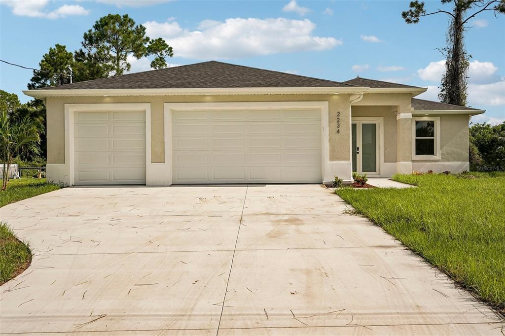 A single-story house with a beige stucco exterior, a three-car garage, and a concrete driveway — 2234 JAMESON AVENUE, NORTH PORT, FL
