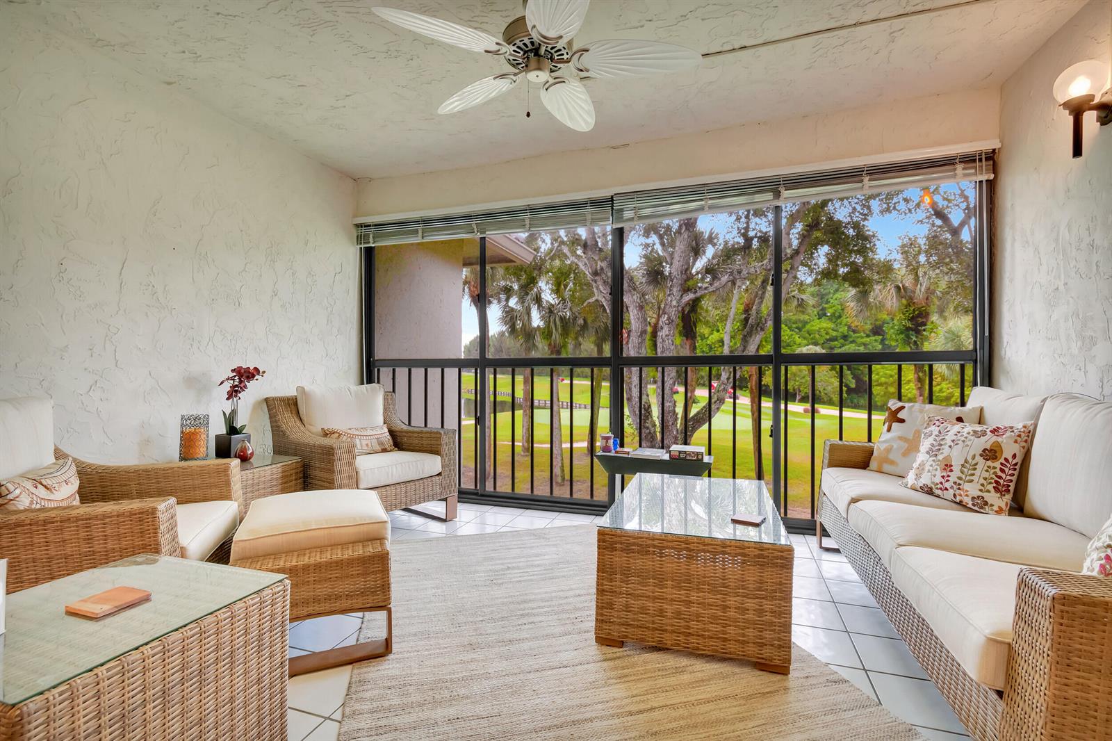 A sunroom features wicker furniture, a glass-topped coffee table, and a view of a golf course — 19 Westgate Lane # 19f, Boynton Beach FL 33436, BOYNTON BEACH, FL
