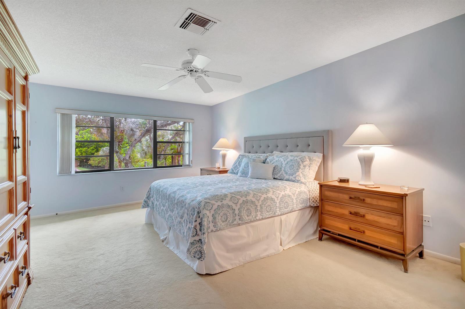 A bedroom features a bed with a tufted headboard, two wooden nightstands, and a window — 19 Westgate Lane # 19f, Boynton Beach FL 33436, BOYNTON BEACH, FL