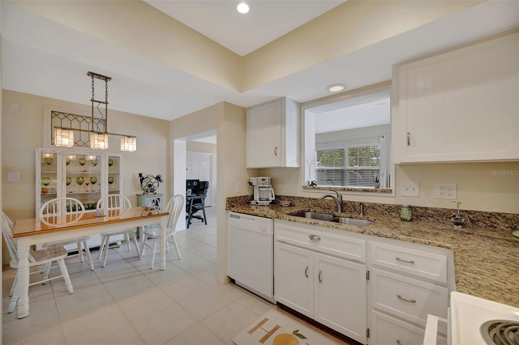 A kitchen with white cabinets, granite countertops, and an adjacent dining area with a hutch — 130 59TH STREET W, BRADENTON, FL
