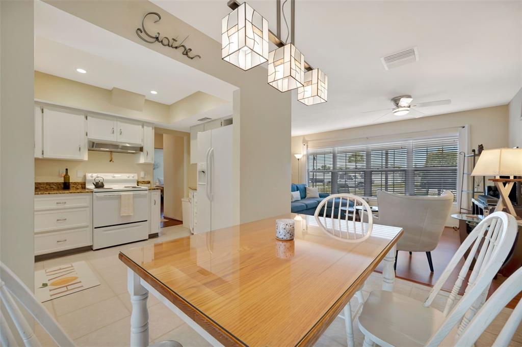 A dining area with a wooden table sits in front of a white kitchen — 130 59TH STREET W, BRADENTON, FL