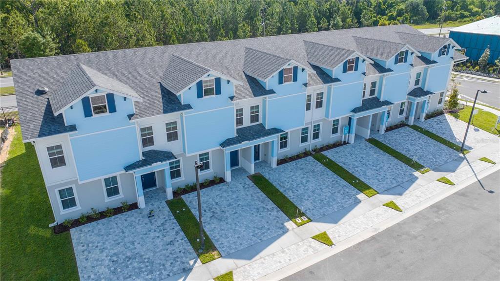 An aerial view of a row of light blue townhomes with paved driveways and landscaping — 183 PEGASUS STREET, DAVENPORT, FL
