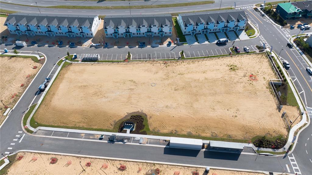 An aerial view shows a vacant, rectangular dirt lot surrounded by paved roads and townhomes — 183 PEGASUS STREET, DAVENPORT, FL
