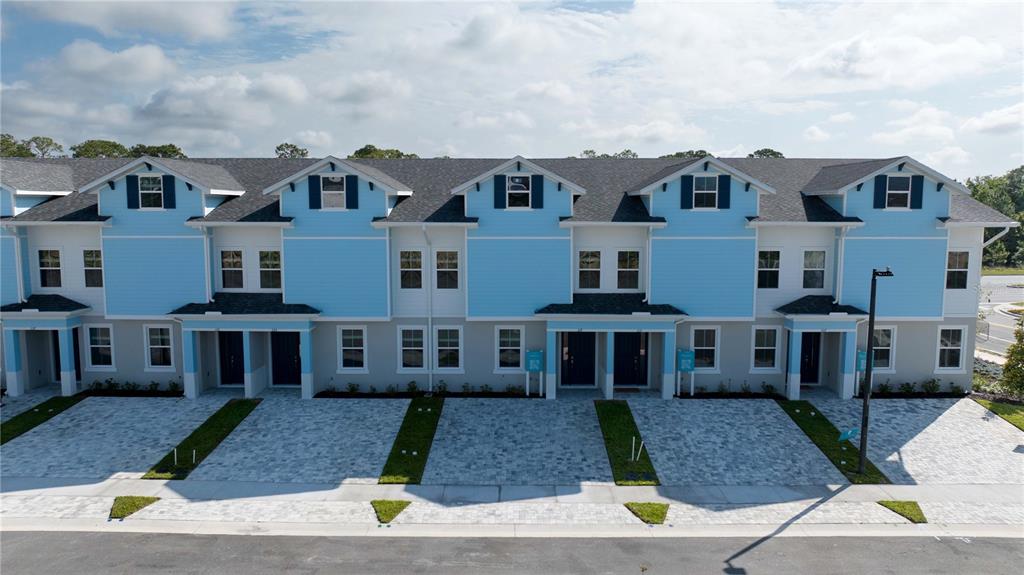 An exterior view of a row of newly constructed blue and gray townhomes with paved driveways — 183 PEGASUS STREET, DAVENPORT, FL