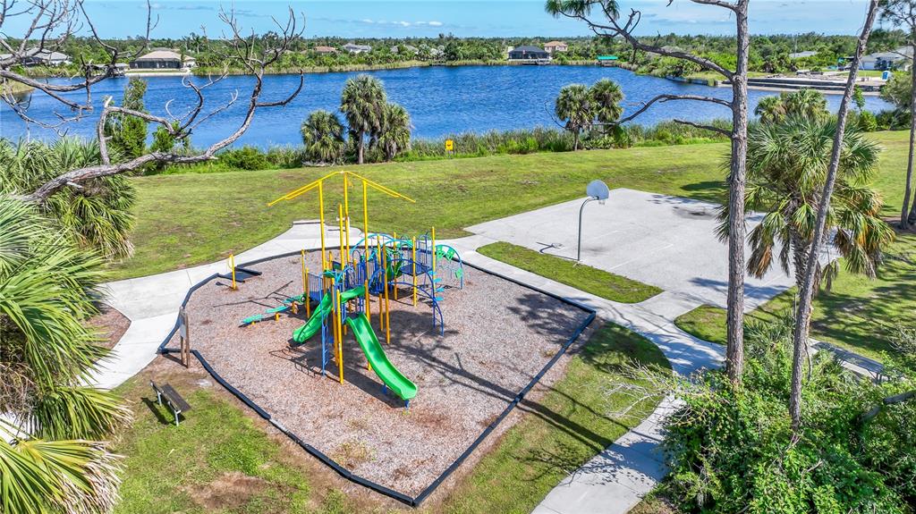 An aerial view shows a playground with slides and a basketball court near a lake — 9357 AGATE STREET, PORT CHARLOTTE, FL