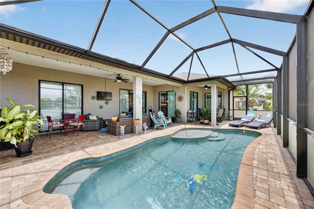 A screened-in patio features a swimming pool, outdoor seating, and paved flooring — 227 LONG MEADOW LANE, ROTONDA WEST, FL
