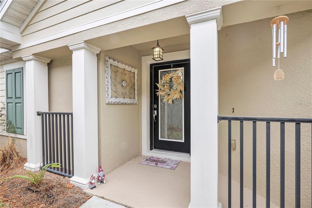 A covered front porch features a black front door, white columns, and black metal railings — 21714 BELGIAN COURT, MOUNT DORA, FL