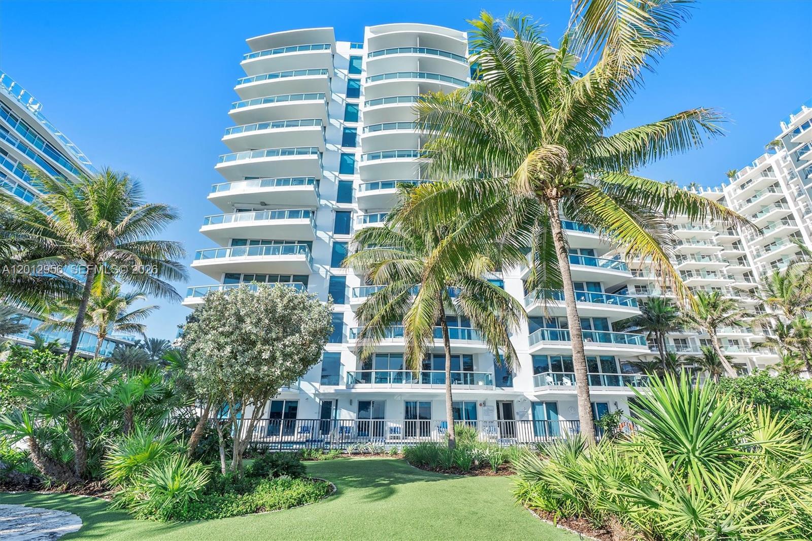 A multi-story white residential building with balconies is surrounded by palm trees and landscaping — 9401 Collins Ave # 505, Surfside FL 33154, SURFSIDE, FL