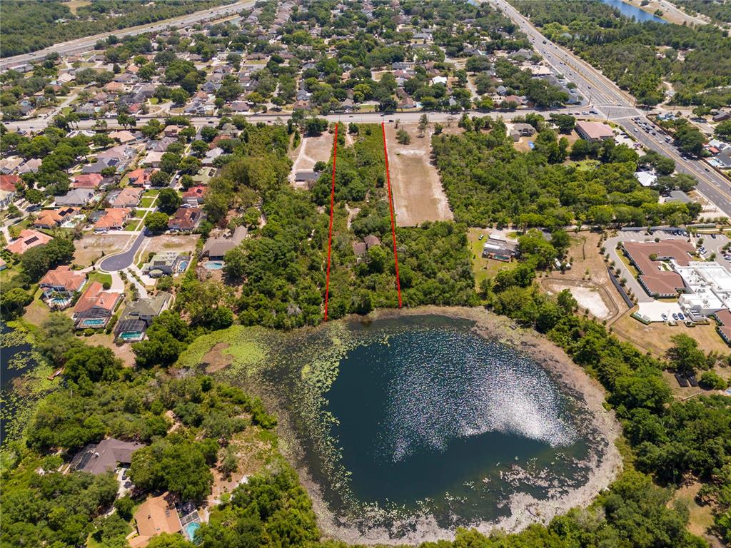An aerial view shows a vacant, tree-lined lot marked by red lines bordering a lake — 4512 S HIAWASSEE ROAD, ORLANDO, FL