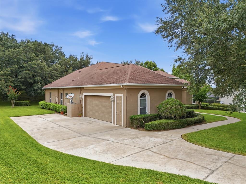 A tan house with a brown shingled roof, a garage, and a concrete driveway — 17535 COBBLESTONE LANE, CLERMONT, FL