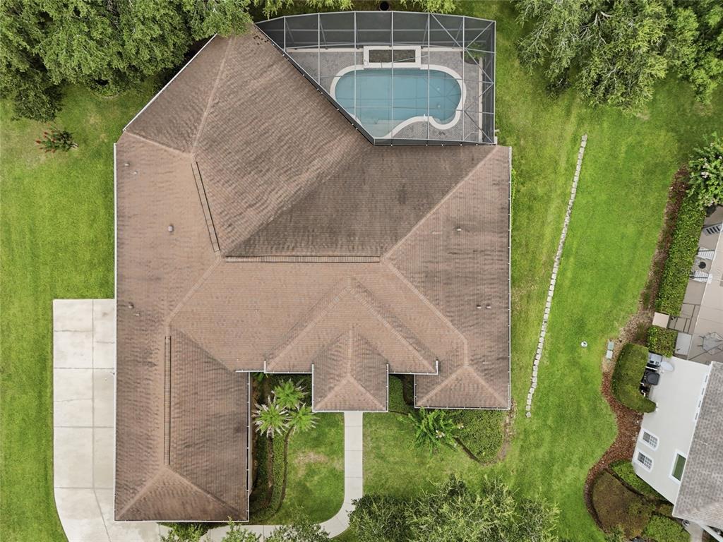 An aerial view shows a house with a brown roof, a screened pool, and landscaping — 17535 COBBLESTONE LANE, CLERMONT, FL