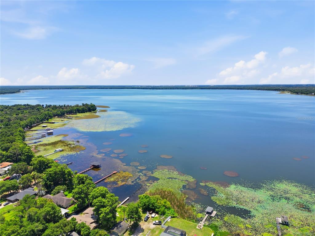An aerial view shows a large lake with docks, vegetation, and surrounding residential properties — HARTMAN RD, LAKE WALES, FL