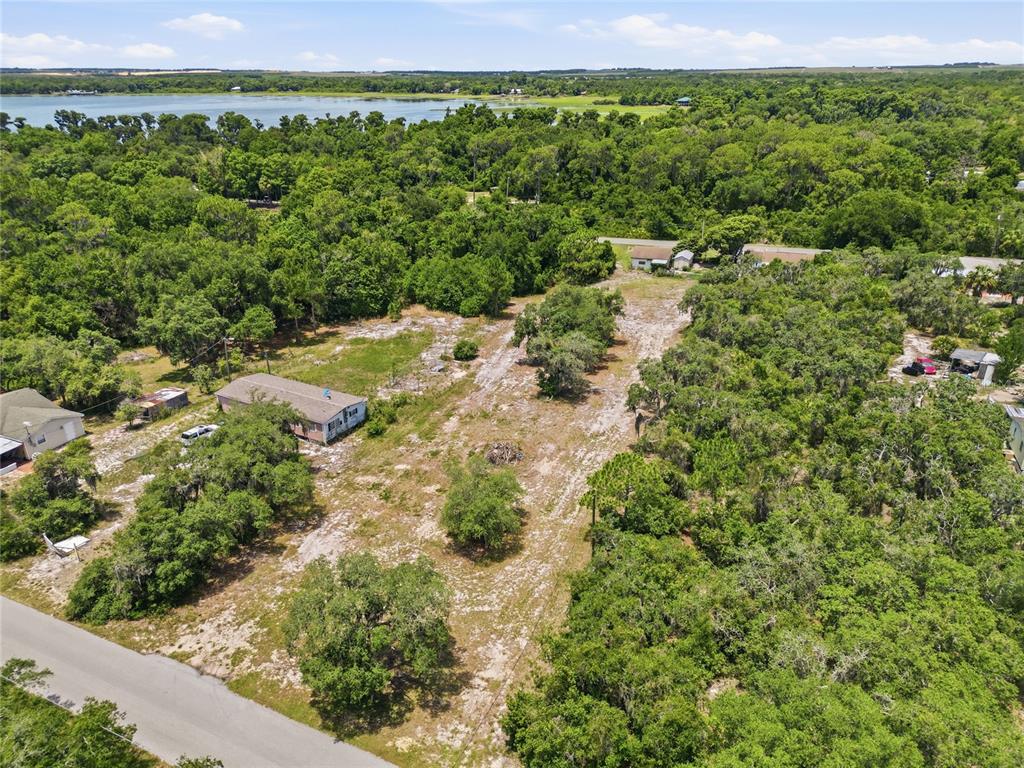 An aerial view shows a cleared residential lot with scattered trees near a lake — HARTMAN RD, LAKE WALES, FL