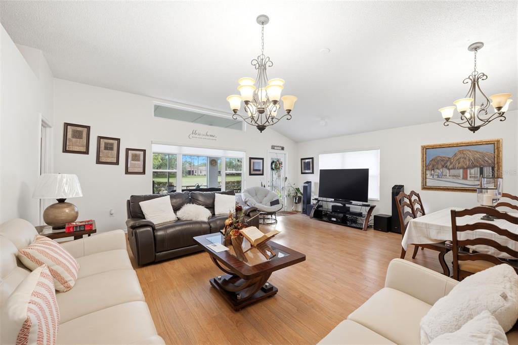 A living and dining area features wood flooring, two chandeliers, and a large television — 14458 TAMARIND LOOP, SPRING HILL, FL