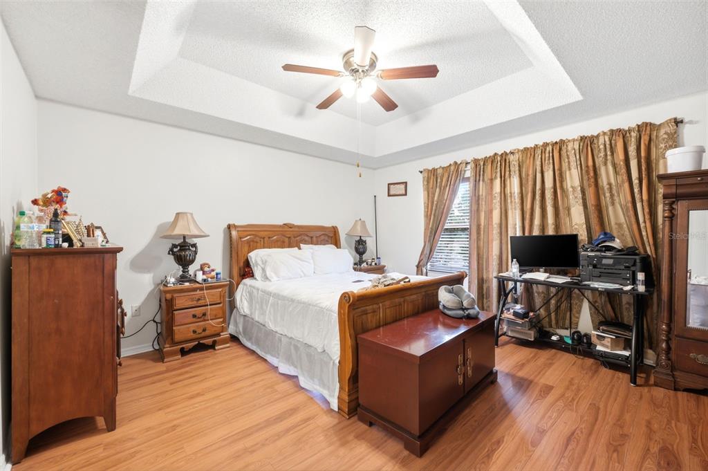 A bedroom with a tray ceiling, wood flooring, a wooden bed frame, and a desk — 14458 TAMARIND LOOP, SPRING HILL, FL