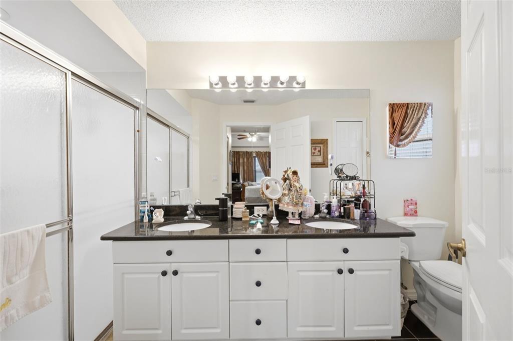 A bathroom features a double vanity with white cabinets, a dark countertop, and a large mirror — 14458 TAMARIND LOOP, SPRING HILL, FL