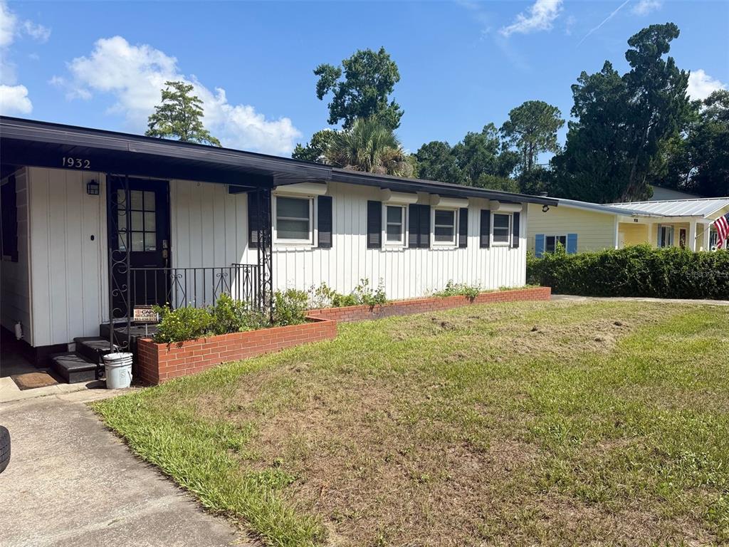 A single-story house with white vertical siding, black shutters, and a brick planter box — 1932 CRESCENT BOULEVARD, ORLANDO, FL