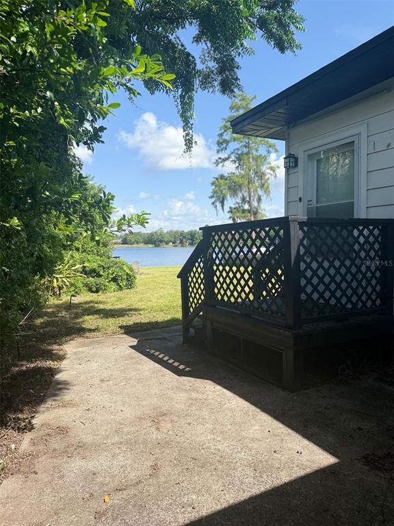A concrete patio sits beside a house with a black lattice deck overlooking a lake — 1932 CRESCENT BOULEVARD, ORLANDO, FL