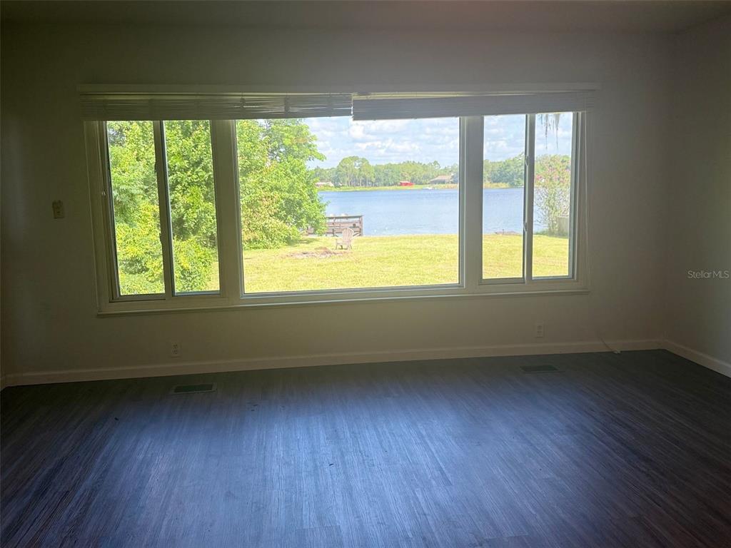 A room with gray wood-look flooring and a large window overlooking a lake — 1932 CRESCENT BOULEVARD, ORLANDO, FL
