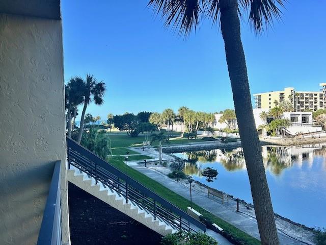 A view from a balcony overlooking a pond, palm trees, and a multi-story building — 1095 GULF OF MEXICO DRIVE UNIT 104, LONGBOAT KEY, FL